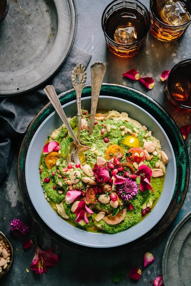 Bowl de hummus con vegetales frescos, flores comestibles y frutos secos, un plato equilibrado acorde al contenido de nutricion saludable en Instagram Chile