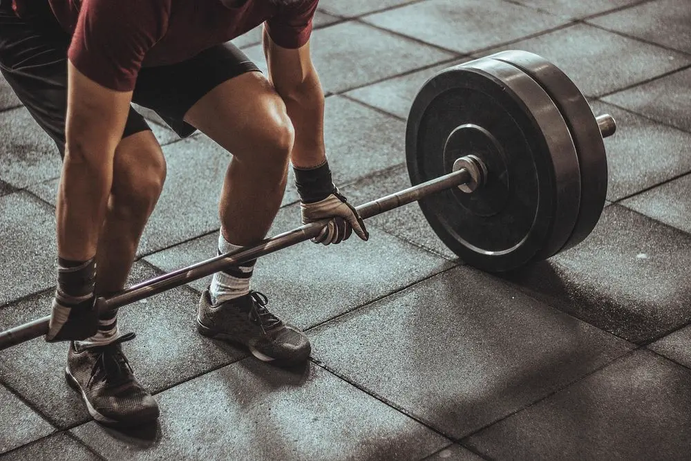 Hombre entrenando con barra de pesas en un gimnasio, referencia al contenido de fitness y preparación física en Instagram Chile