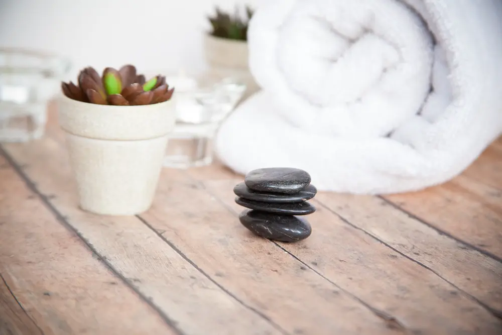 Toalla blanca enrollada y piedras de spa sobre una mesa de madera, referencia al contenido de cosmetología y cuidado facial en Instagram Chile