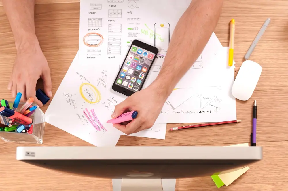 Escritorio con bocetos de apps, celular y marcadores, referencia al marketing digital y contenido para Instagram en Chile
