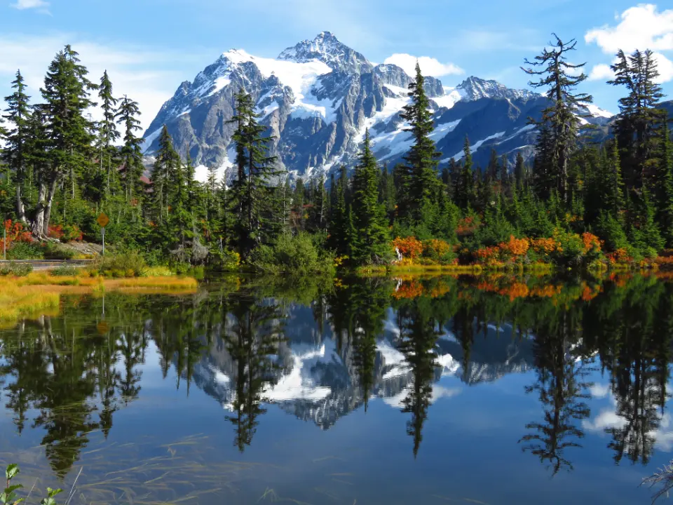 Lago de aguas calmas que refleja una montaña nevada y un bosque, referencia al contenido de viajes y lifestyle en Instagram Chile