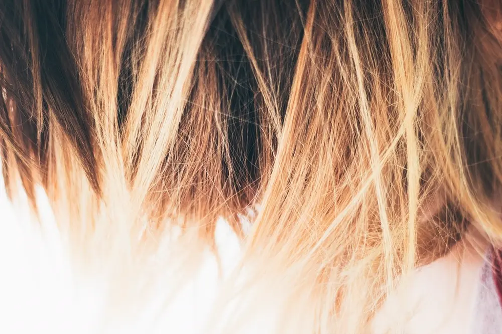 Primer plano de un cabello castaño con mechas rubias tipo balayage, referencia al contenido de colorimetría capilar en Instagram Chile